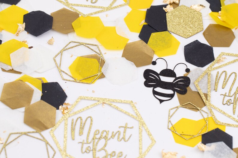 May include: Gold and black confetti with a bee and a hexagon with the text "Meant to Bee".