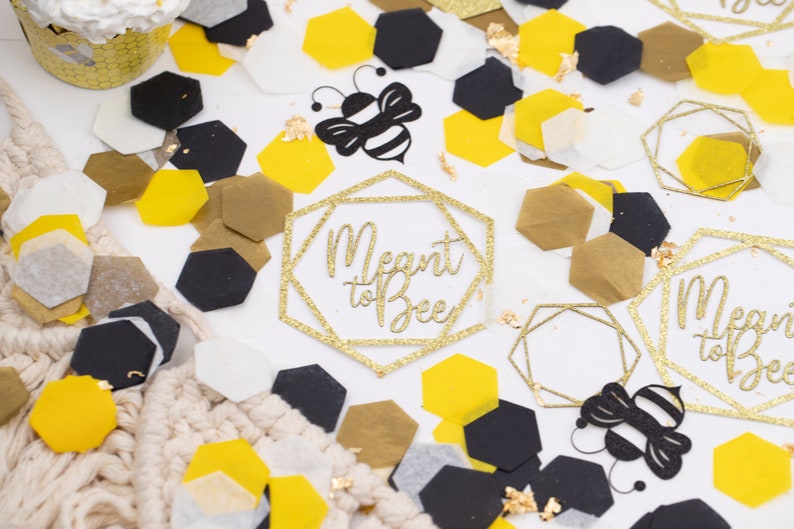 May include: Gold glitter geometric shapes with the text "Meant to Bee" and black and yellow bee cutouts on a white background with gold, black, and white confetti.
