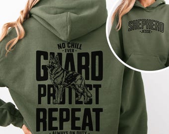 May include: An olive green hooded sweatshirt featuring a black graphic on the back of a German Shepherd dog with the text NO CHILL EVER GUARD PROTECT REPEAT ALWAYS ON DUTY GSD. The front chest area displays the text SHEPHERD JESSE.
