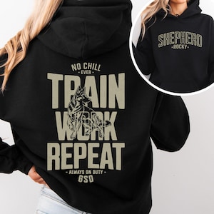 May include: Black hoodie with the text "TRAIN WORK REPEAT" and a German Shepherd graphic. The hoodie also features the text "NO CHILL EVER" and "ALWAYS ON DUTY - GSD". A smaller image shows the word "SHEPHERD" above "ROCKY".