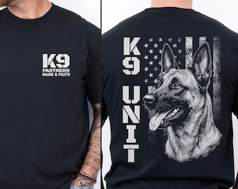 May include: A black t-shirt featuring a white K9 PARTNERS MARK & FAITH logo on the front chest. The back displays a large graphic of a German Shepherd dog, the text K9 UNIT, and a distressed American flag design in white ink on black fabric.