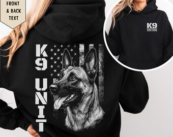 May include: A black hooded sweatshirt featuring a large graphic on the back of a German Shepherd dog head, a distressed American flag, and the text K9 UNIT. The front chest area displays the text K9 PARTNERS JESS & KOVA in white.