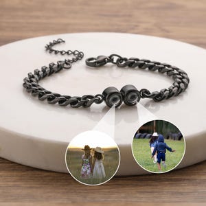 May include: A dark gray chain bracelet with a magnetic clasp. The bracelet is displayed on a white surface. Two circular inset images show children playing outdoors.