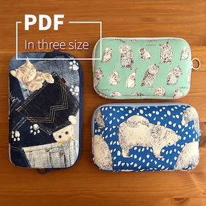 Puede incluir: Tres estuches con cremallera con diferentes diseños. El primer estuche es azul con un patrón de mezclilla y dos gatitos blancos. El segundo estuche es verde con un patrón de búho blanco. El tercer estuche es azul con un patrón de oso polar blanco. El texto "PDF In three size" está en un cuadro blanco sobre los estuches.