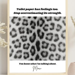 Puede incluir: Impresión enmarcada con un borde crema. La impresión presenta un fondo de estampado de leopardo y texto que dice: "El papel higiénico también tiene sentimientos. Deja de sobreestimar su fuerza. Sabes de qué estoy hablando. Miau."