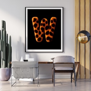 Könnte beinhalten: Gerahmter Kunstdruck mit dem stilisierten Buchstaben "W". Der Buchstabe ist in einem orange-schwarzen Leopardenmuster auf schwarzem Hintergrund dargestellt. Das Kunstwerk ist in einem modernen Interieur platziert, geeignet für die Wanddekoration.