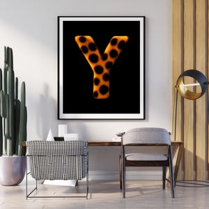Könnte beinhalten: Gerahmter Druck mit dem Buchstaben "Y". Der Buchstabe ist in leuchtendem Orange mit schwarzen Punkten auf schwarzem Hintergrund dargestellt. Das Kunstwerk ist in einem schwarzen Rahmen präsentiert.