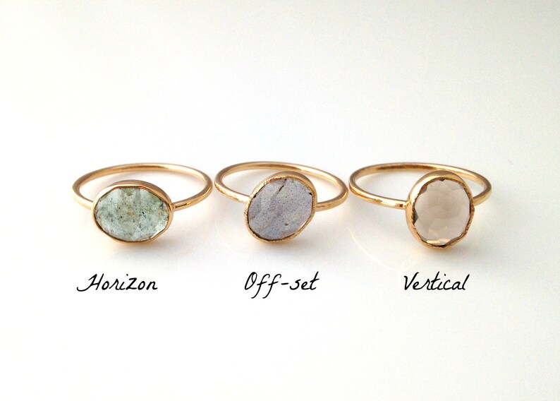 Op de afbeelding: Drie gouden ringen met verschillende ovale stenen in kleur. De ringen zijn gelabeld met "Horizon", "Off-set" en "Vertical".