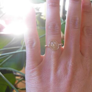 Op de afbeelding: Een gouden ring met een heldere, ovale edelsteen. De edelsteen heeft een lichtbruine kleur en is gezet in een eenvoudige band.