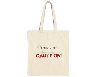 Może przedstawiać: Beżowa torba typu tote z nadrukiem "I am an Introvert Proceed with CAUTION!" w kolorze czerwonym.