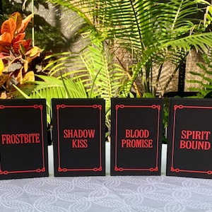 May include: Six black cards with red text, each card has a different title from the Vampire Academy series: Vampire Academy, Frostbite, Shadow Kiss, Blood Promise, Spirit Bound, Last Sacrifice.