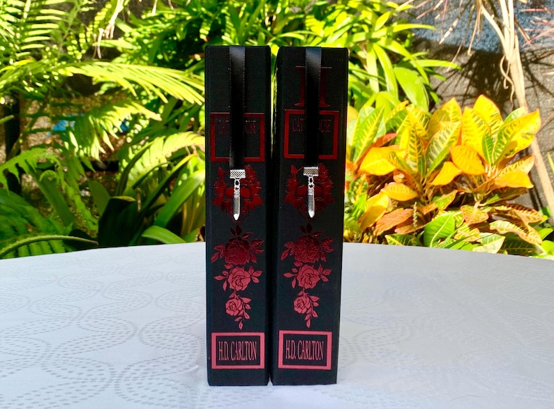 May include: Two black boxes with red rose designs and silver charms. The boxes have the text "HD CARLTON" printed on the bottom.