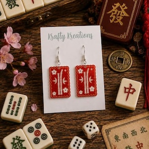 May include: Red rectangular earrings with white bamboo and flower designs are displayed on a white card that reads "Krafty Kreations." The image includes Mahjong tiles, dice, and a small wooden box with Chinese characters.