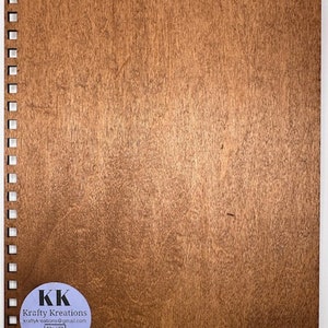 May include: A brown wooden board with a white spiral binding on the left side. A white circle sticker with the text "KK Krafty Kreations" and a QR code is on the bottom left corner.