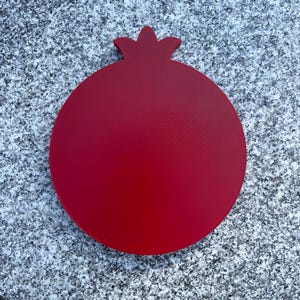 May include: A red wooden pomegranate shaped cutting board.