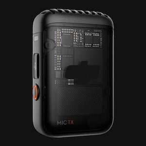 May include: A black microphone with a transparent casing revealing the internal circuitry. The microphone has an orange button and the text "MIC TX" is printed on the bottom.