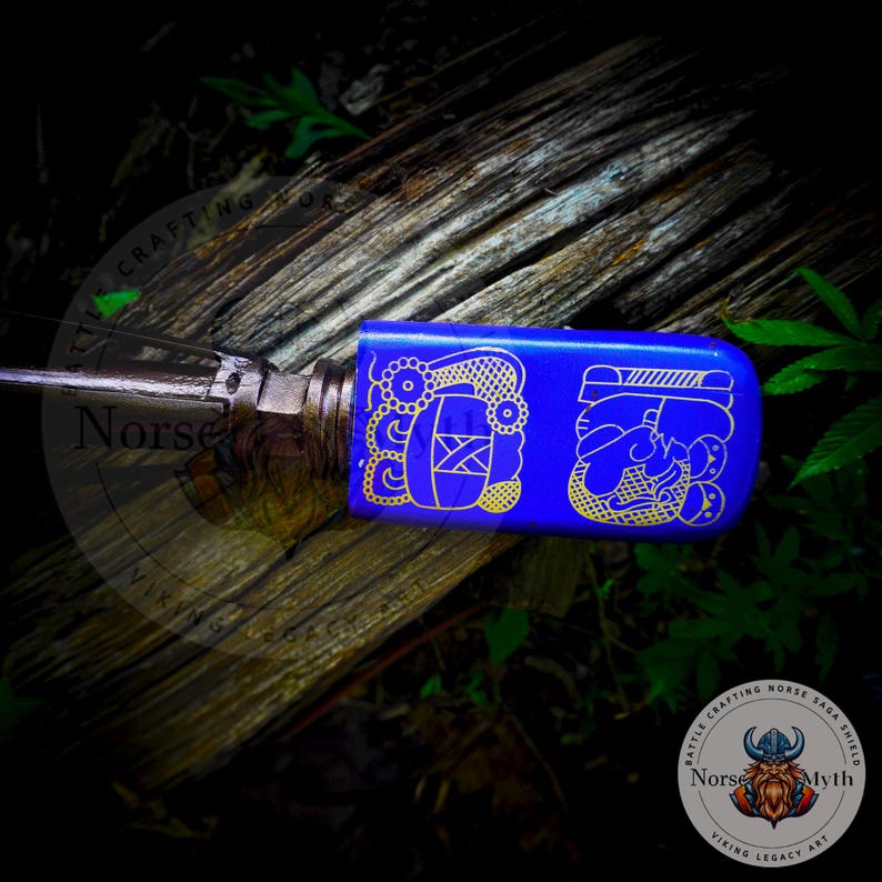 May include: A blue and gold decorative knife handle with intricate designs. The handle is made of wood and has a blue finish with gold accents. The design on the handle is a stylized representation of a Viking ship.