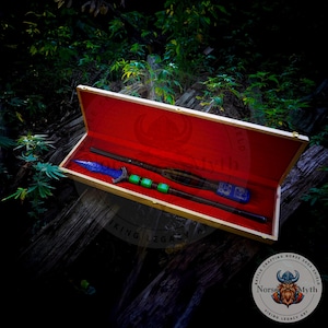 May include: A wooden box with a red velvet lining, containing a long, dark blue and green spear with a decorative handle. The box has the text "Viking Legacy Art" and "Battle Crafting Horse Saga Shield Norse Myth" printed on it.