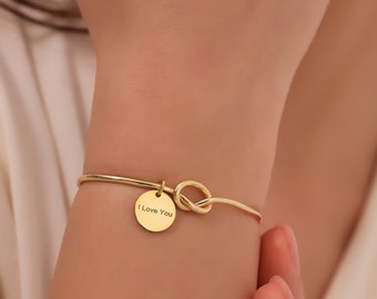 May include: Gold bracelet with a knot design and a round charm that says "I Love You".