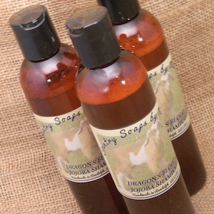 May include: Three brown glass bottles with labels that say "Country Soaps by" and "Dragon's Blood Jojoba Shampoo Handmade in Randolph, WI".