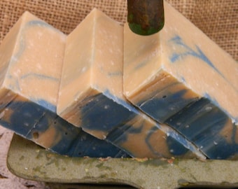 Puede incluir: Tres barras de jabón hechas a mano con un patrón de remolino azul y beige. El jabón está apilado uno encima del otro.