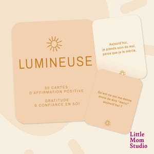 May include: A set of affirmation cards with a light peach background. The main card reads "LUMINEUSE" in a gold font, with text below stating "50 CARTES D'AFFIRMATION POSITIVE GRATITUDE & CONFIANCE EN SOI". Two smaller cards display French text. The Little Mom Studio logo is in the bottom right.