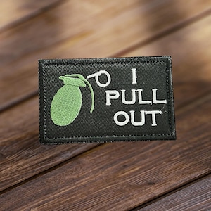 May include: Black embroidered patch with a green grenade and the text "I PULL OUT" in white.