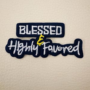 May include: Two embroidered patches with the words "BLESSED" and "Highly Favored" in white thread on a navy blue background. The word "Blessed" is in a rectangular patch, and "Highly Favored" is in a cursive font.