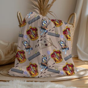 Könnte beinhalten: Eine braune und beigefarbene Wolldecke mit einem sich wiederholenden Muster aus einem blauen Hund, der einen Zauberstab hält, einem Gryffindor-Wappen und dem Text "Platform 9 3/4".