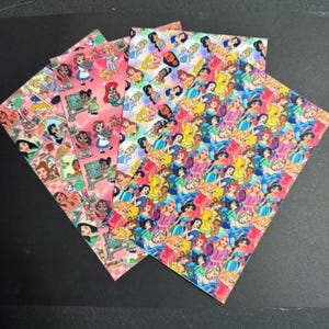 May include: Four sheets of patterned paper featuring various Disney princesses. The sheets display a collage of princess illustrations in vibrant colors, including pink, yellow, blue, and red. The designs showcase multiple princesses in a repeating pattern.