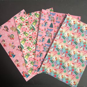 May include: Four sheets of patterned paper with a pink background. The patterns include Disney princesses, Stitch, Bluey characters, and Hello Kitty, all in festive Christmas designs. Each sheet features a different repeating pattern with holiday elements.