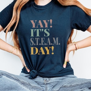 May include: A navy blue t-shirt with the text "YAY! IT'S S.T.E.A.M. DAY!" in colorful block letters.