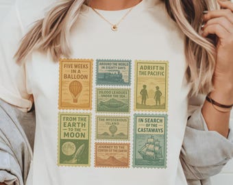May include: Cream-colored t-shirt featuring nine postage stamp designs with travel-themed illustrations and text. The stamps include images of a hot air balloon, a train, a ship, and text such as "Five Weeks in a Balloon" and "Around the World in Eighty Days."