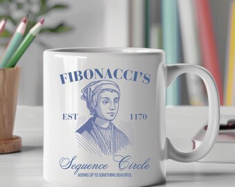 May include: White ceramic mug featuring a blue illustration of a historical figure and the text "FIBONACCI'S", "EST 1170", and "Sequence Circle". The mug also includes the phrase "ADDING UP TO SOMETHING BEAUTIFUL".