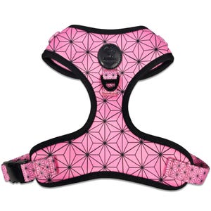 May include: A pink pet harness featuring a black geometric starburst pattern and black trim. The harness includes a black D-ring for leash attachment and a circular black logo patch at the center chest area with the text WAGS AND WIGGLES.