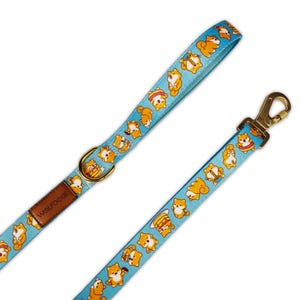 May include: A blue dog leash with a pattern of Shiba Inu dogs eating various foods. The leash has a gold metal clip and a brown leather tag that says "Wolfdoge".