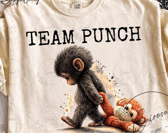 May include: A cream-coloured t-shirt with the text "TEAM PUNCH" in black. The shirt features a watercolour illustration of a sad-looking monkey walking and pulling a stuffed animal. The monkey is grey and brown, and the stuffed animal is orange.
