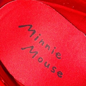 Puede incluir: Primer plano del interior de un zapato rojo. La plantilla es roja con las palabras "Minnie Mouse" impresas en escritura cursiva negra. El interior del zapato tambi&eacute;n es rojo.