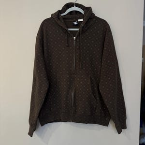 May include: A brown zip-up hoodie with a diamond pattern and the DC logo on the front.