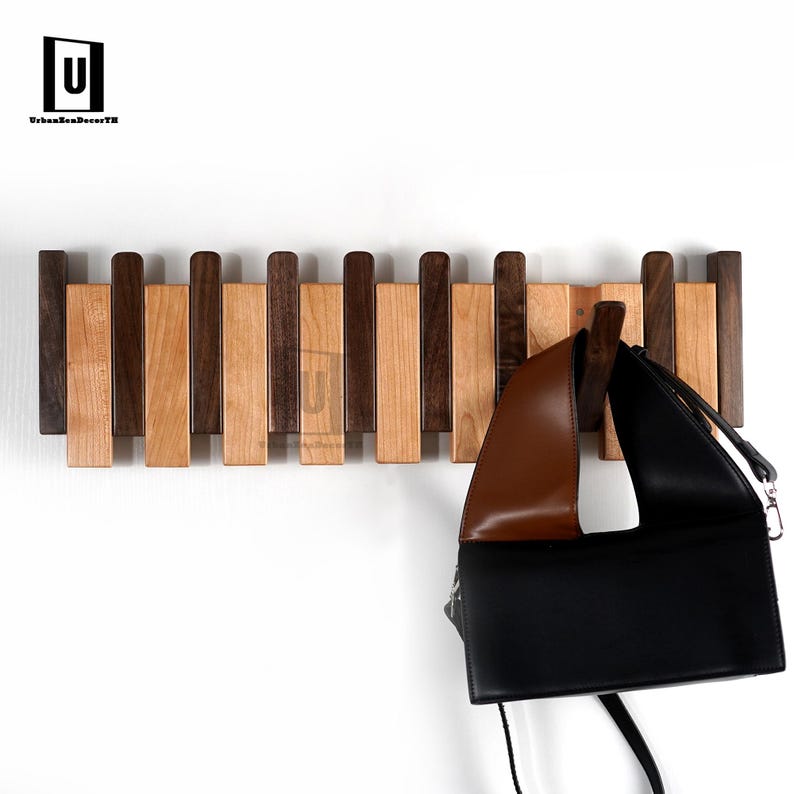 May include: A wooden wall-mounted coat rack with alternating dark and light wood slats. A brown and black handbag hangs from the rack. The logo "UrbanZenDecorTH" is in the upper left corner.