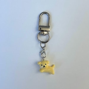 May include: A yellow dog keyring with a silver swivel clasp and a silver loop.