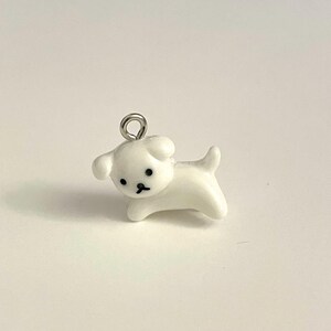 May include: White ceramic dog charm with black eyes and a silver loop for hanging.