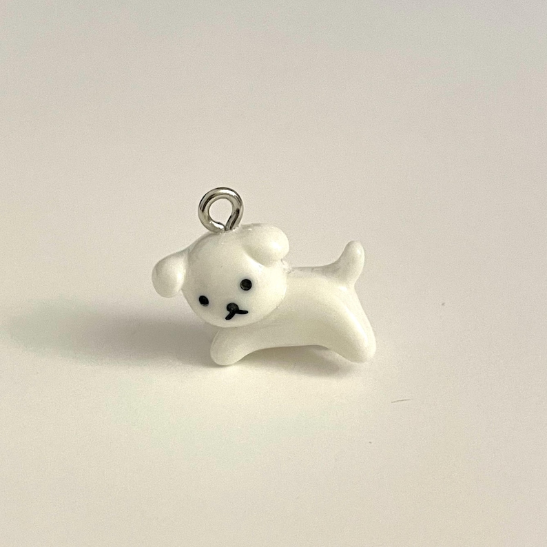 May include: White ceramic dog charm with black eyes and a silver loop for hanging.