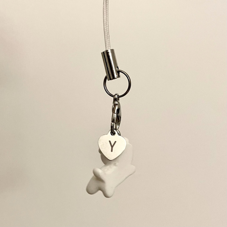 May include: White ceramic charm with a heart-shaped tag that says "Y" attached to a silver chain and a silver cord.