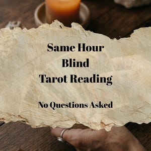 May include: A lit orange candle sits on a wooden surface, with a torn paper overlay featuring the text "Same Hour Blind Tarot Reading, No Questions Asked." A hand with a ring is visible.