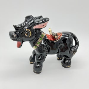 May include: Black ceramic donkey figurine with a red saddle, green and gold accents, and large, expressive eyes.