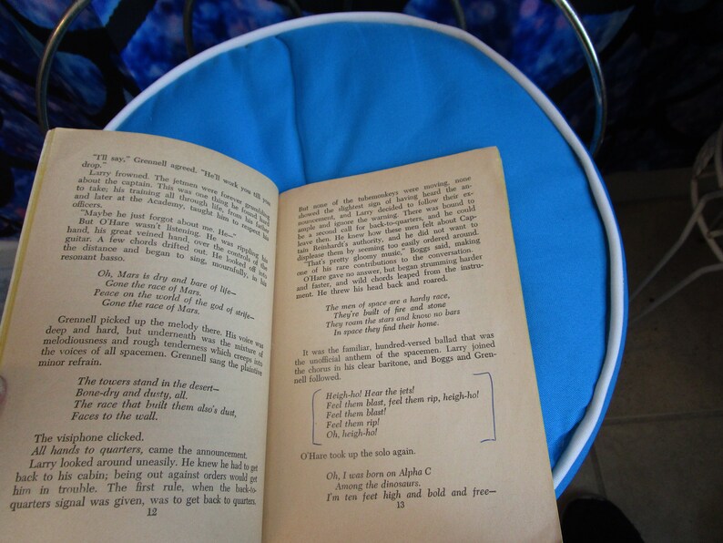 May include: A close-up of a book page with text about the race of Mars. The text reads "Oh, Mars is dry and bare of life - Gone the race of Mars. Peace on the world of the god of strife - Gone the race of Mars."