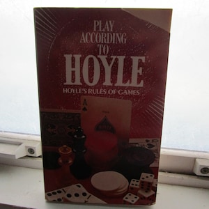May include: A red book titled "Play According to Hoyle" with the subtitle "Hoyle's Rules of Games". The cover features a playing card, dice, dominoes, and chess pieces.