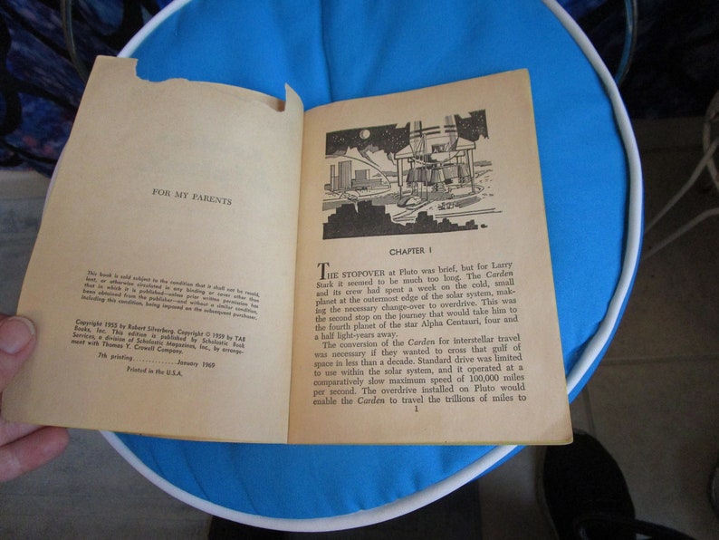 May include: A vintage paperback book titled "The Carden" with a black and white illustration of a spaceship on the cover. The book is open to the first chapter, titled "The Stopover".