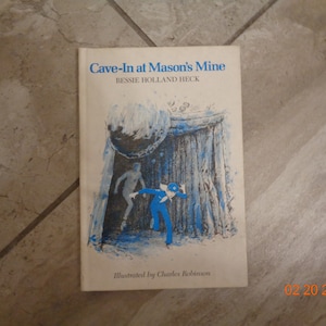 May include: A book cover with a blue and white illustration of a person running away from a cave-in. The title of the book is "Cave-In at Mason's Mine" by Bessie Holland Heck. The book is illustrated by Charles Robinson.